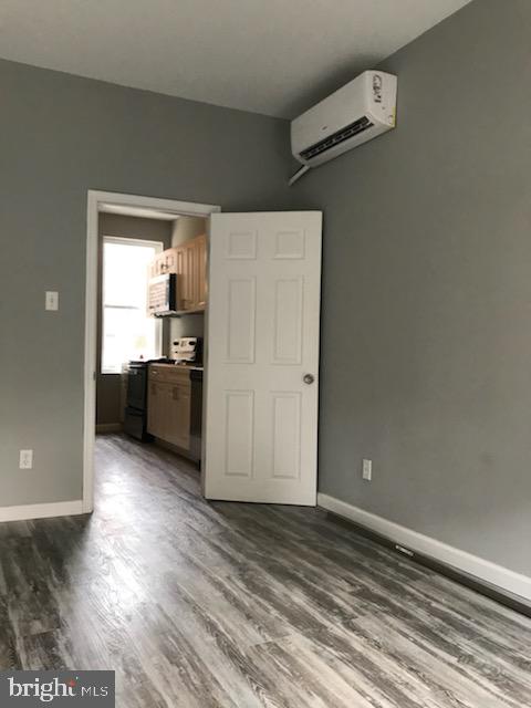 spare room with a wall mounted AC and dark hardwood / wood-style floors