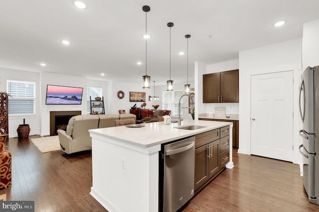 kitchen with pendant lighting, sink, a center island with sink, appliances with stainless steel finishes, and dark hardwood / wood-style floors