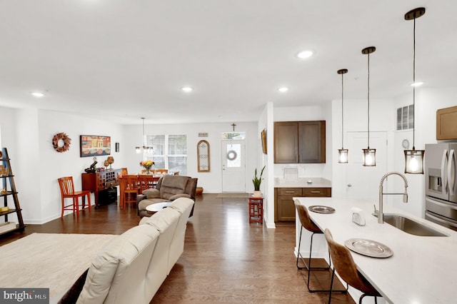 living room featuring an inviting chandelier, sink, and dark hardwood / wood-style flooring