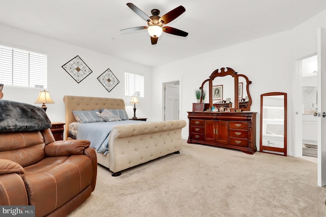 bedroom with ceiling fan, light colored carpet, connected bathroom, and multiple windows