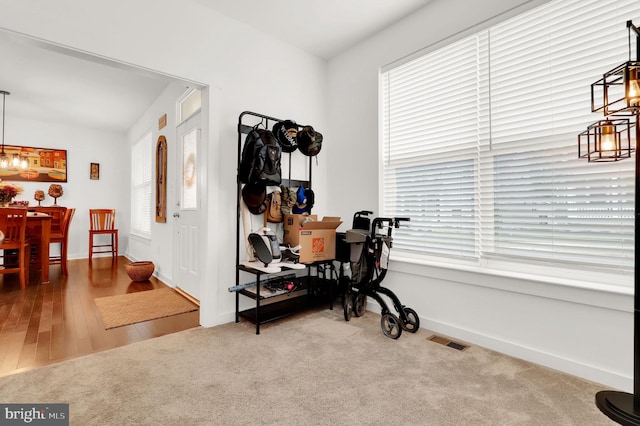 workout area featuring plenty of natural light, an inviting chandelier, and hardwood / wood-style flooring