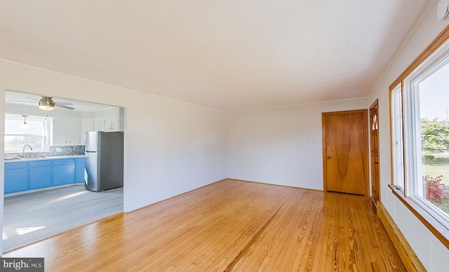 unfurnished living room featuring ceiling fan, light hardwood / wood-style flooring, and sink