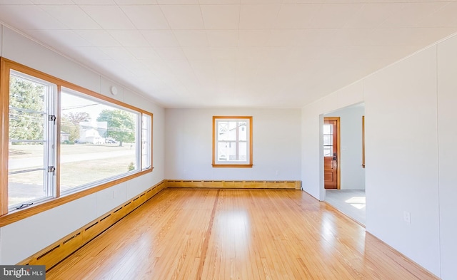 spare room featuring a baseboard heating unit and light hardwood / wood-style floors