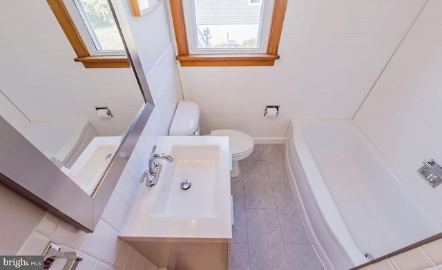 bathroom featuring a tub to relax in, plenty of natural light, and toilet