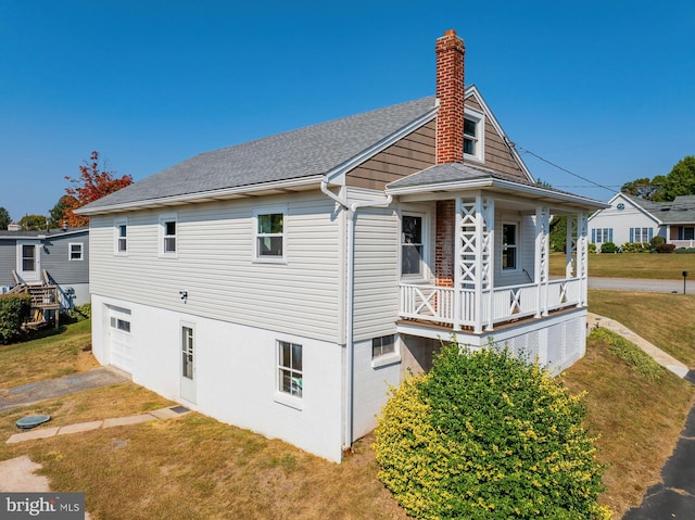 view of side of home featuring a lawn and covered porch