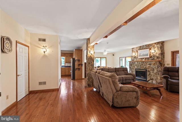 living room with ceiling fan, a fireplace, beam ceiling, and wood-type flooring