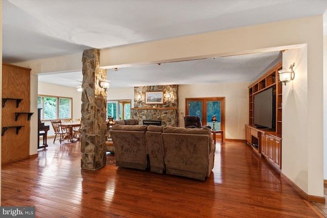 living room featuring dark wood-type flooring and a stone fireplace