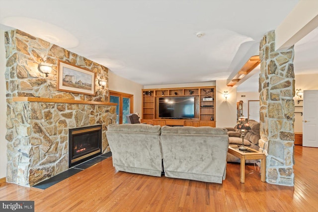 living room with a stone fireplace and hardwood / wood-style floors