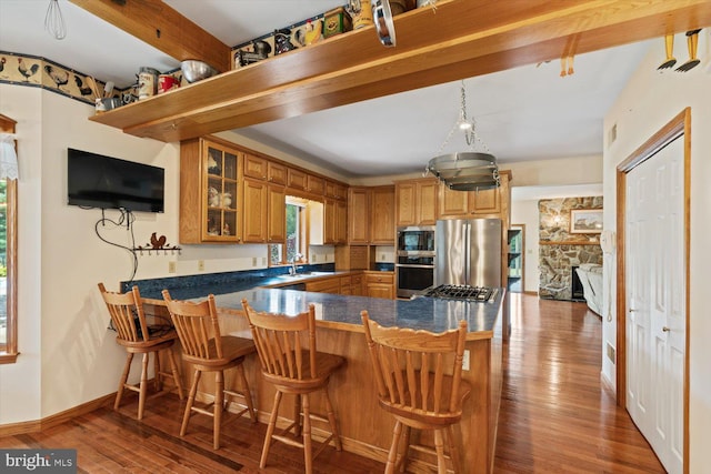 kitchen featuring wood-type flooring, kitchen peninsula, and stainless steel appliances