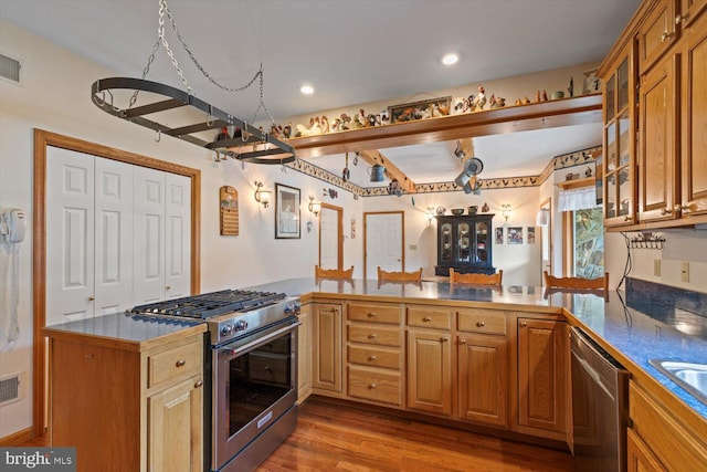 kitchen featuring appliances with stainless steel finishes, light hardwood / wood-style floors, and kitchen peninsula