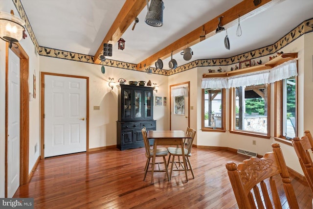 dining space with beamed ceiling and hardwood / wood-style flooring