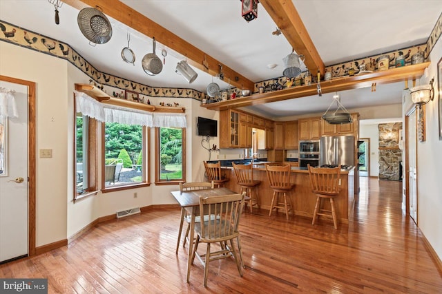 dining space featuring beamed ceiling and light hardwood / wood-style flooring