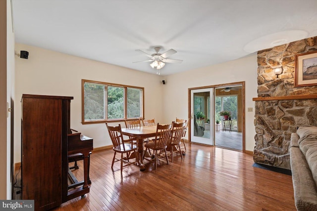 dining area featuring ceiling fan, a fireplace, and hardwood / wood-style floors