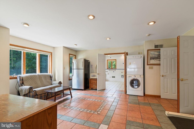 kitchen with stainless steel refrigerator, stacked washer and dryer, and tile patterned floors