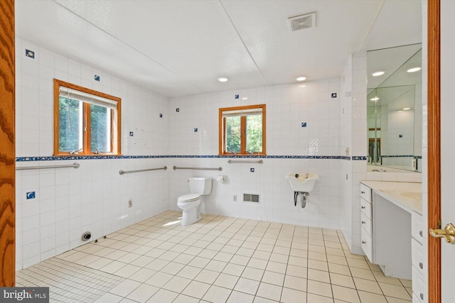 bathroom with tile walls, tile patterned flooring, vanity, and toilet