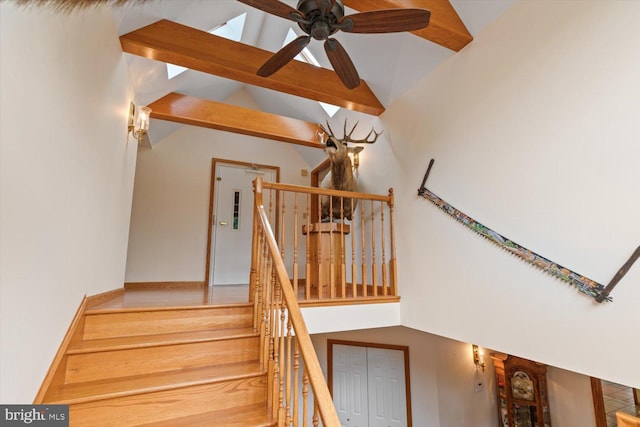 staircase with beam ceiling, ceiling fan, and high vaulted ceiling