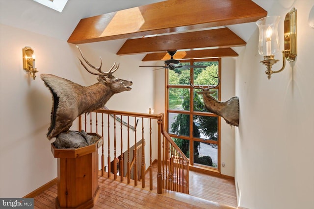 stairs featuring wood-type flooring, a skylight, and beamed ceiling