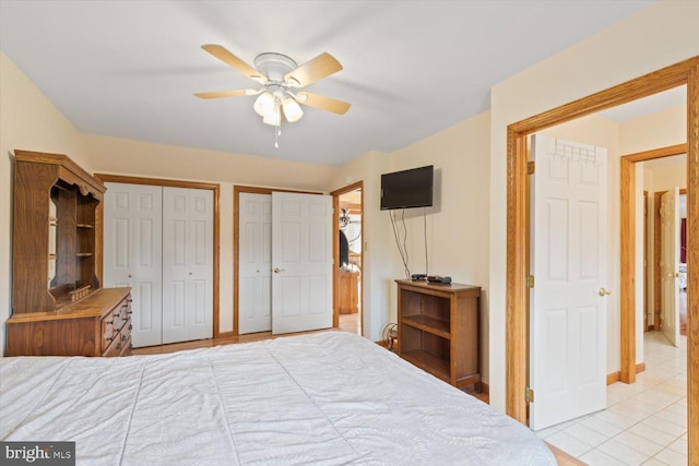 bedroom featuring ceiling fan, multiple closets, and light tile patterned floors