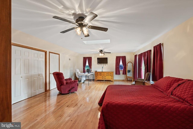 bedroom featuring hardwood / wood-style floors, ceiling fan, and a skylight