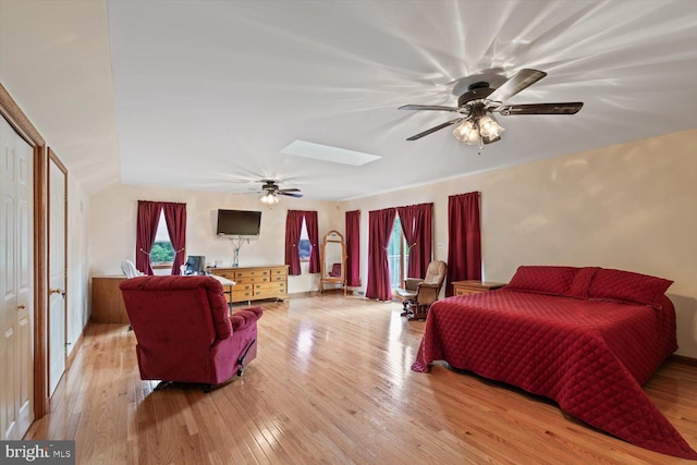 bedroom with ceiling fan, light hardwood / wood-style flooring, a skylight, and a closet