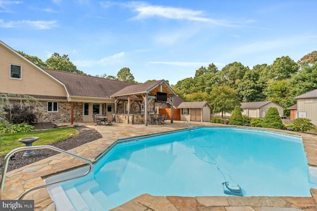 view of swimming pool with a patio and an outbuilding