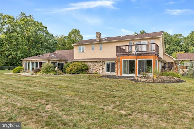 rear view of house featuring a balcony and a lawn