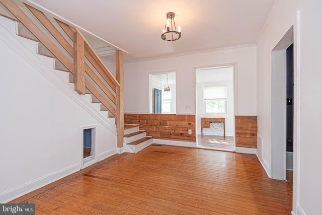 entrance foyer featuring hardwood / wood-style flooring, wooden walls, crown molding, and a chandelier