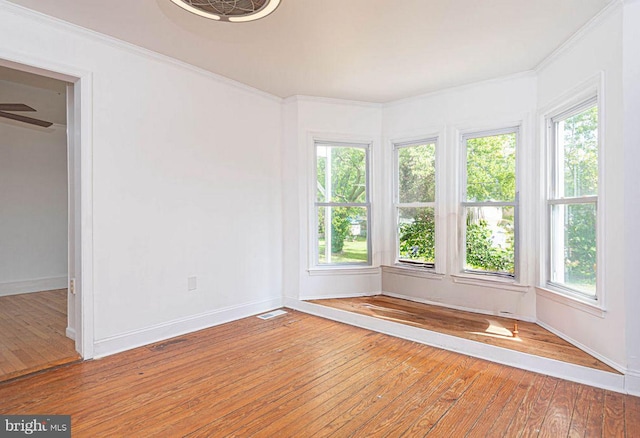 spare room featuring plenty of natural light, ornamental molding, and hardwood / wood-style flooring