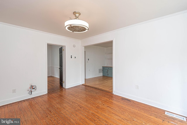 spare room with wood-type flooring and crown molding