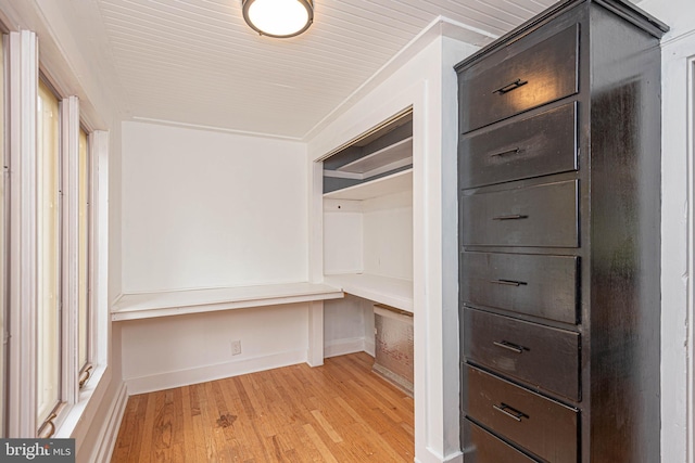 walk in closet with light wood-type flooring and built in desk