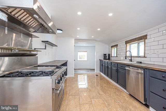 kitchen with wall chimney exhaust hood, wooden counters, crown molding, sink, and stainless steel appliances