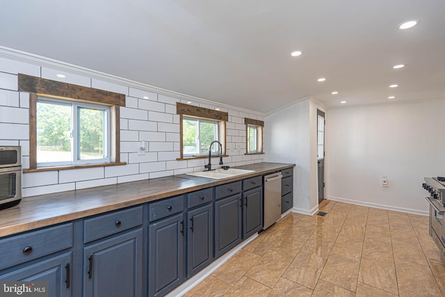 kitchen with dishwasher, sink, wooden counters, and a wealth of natural light