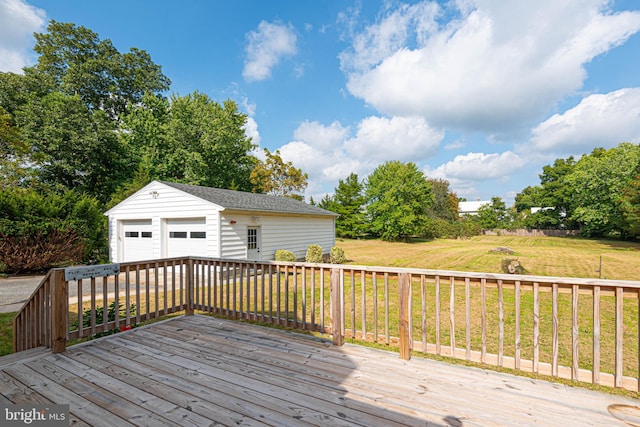 wooden terrace featuring a garage, a yard, and an outbuilding