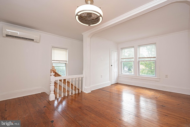 empty room with wood-type flooring, ornamental molding, and a wall mounted AC