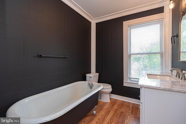 bathroom featuring vanity, crown molding, toilet, hardwood / wood-style flooring, and a tub