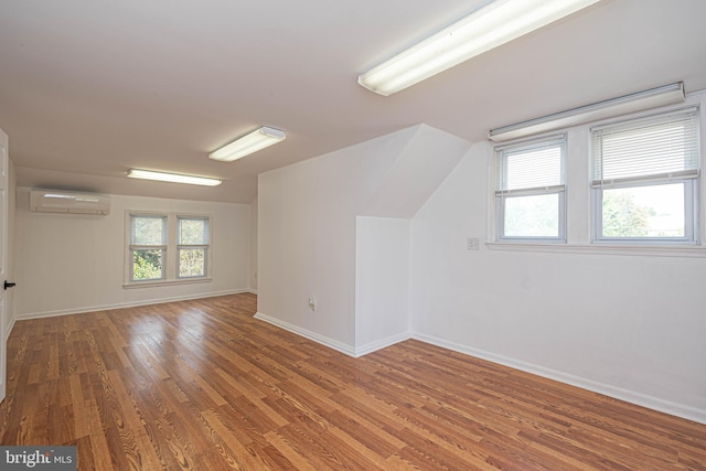 additional living space with hardwood / wood-style floors and an AC wall unit