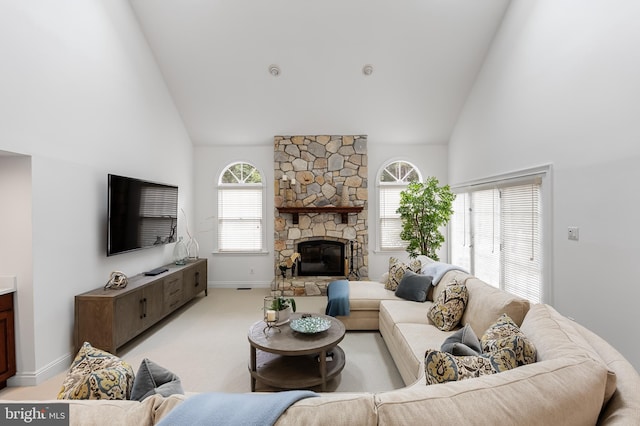 carpeted living room with a stone fireplace and high vaulted ceiling