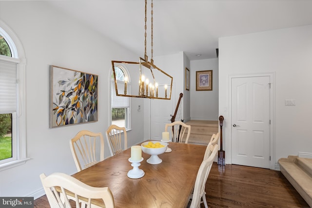 dining area featuring an inviting chandelier, lofted ceiling, and dark hardwood / wood-style flooring