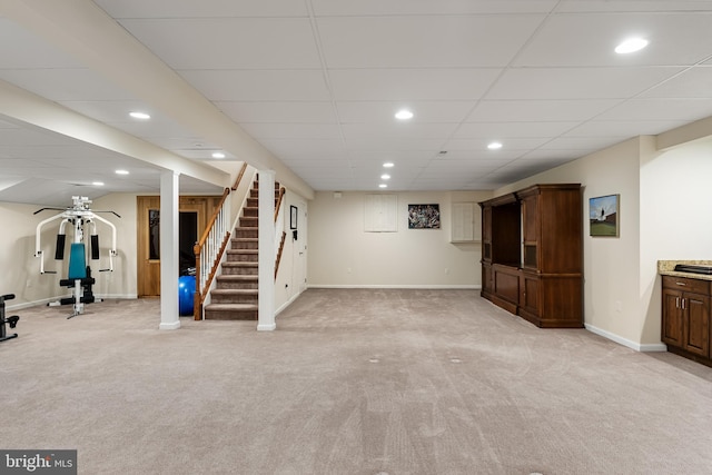 basement featuring a drop ceiling and light colored carpet