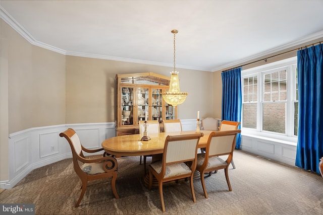 carpeted dining space featuring a chandelier and crown molding