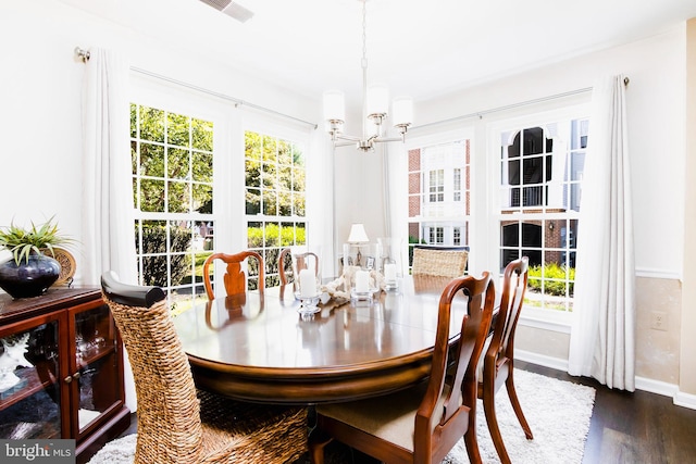 dining area with plenty of natural light, dark hardwood / wood-style flooring, and a chandelier