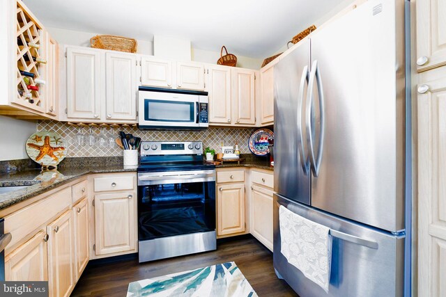 kitchen featuring dark stone counters, backsplash, dark hardwood / wood-style flooring, and stainless steel appliances