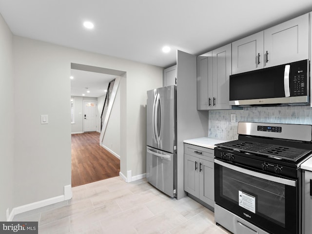 kitchen featuring gray cabinets, stainless steel appliances, decorative backsplash, and light hardwood / wood-style flooring