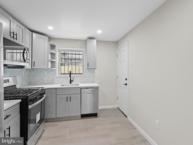 kitchen with light tile patterned flooring, tasteful backsplash, sink, gray cabinetry, and stainless steel appliances