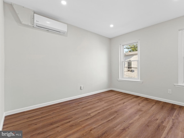 unfurnished room featuring wood-type flooring and a wall unit AC