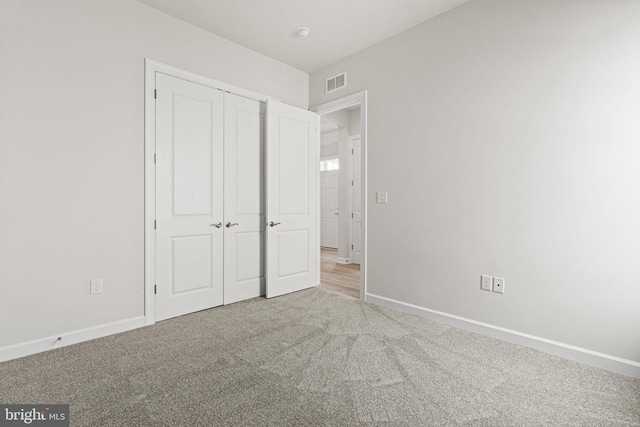 unfurnished bedroom with light carpet and a closet