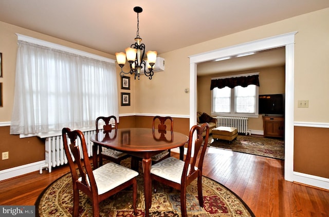 dining area featuring radiator, a chandelier, and wood-type flooring