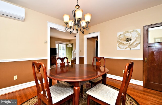 dining area with a wall mounted air conditioner, wood-type flooring, and a notable chandelier