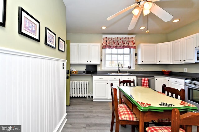 kitchen with stainless steel appliances, white cabinets, and radiator heating unit