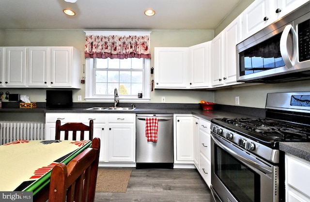 kitchen with radiator, sink, stainless steel appliances, and white cabinets